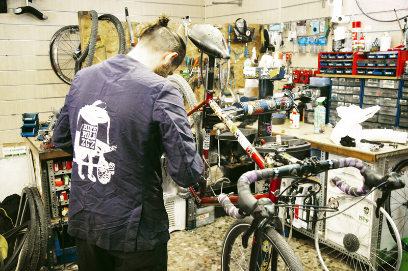 Trabajador en la tienda de reparación de bicicletas FixiDixi.